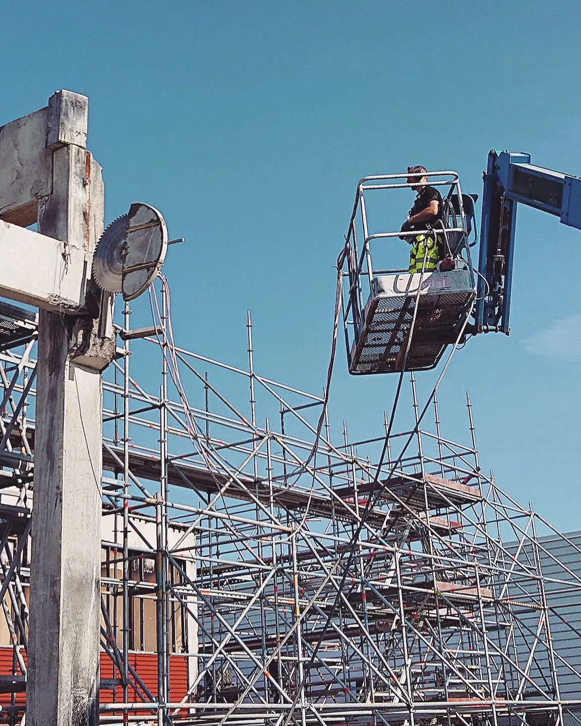 Rivning av betongbyggnad med sågklinga och arbete från mobillift